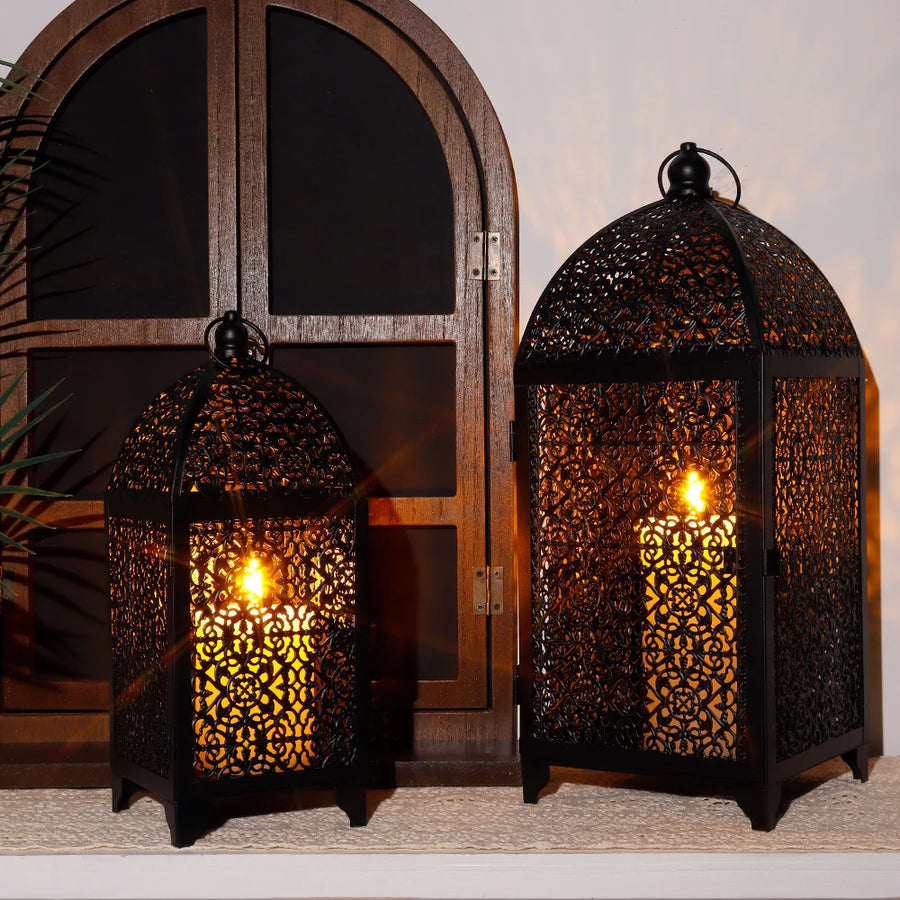 Lot de deux grandes lanternes noires en métal présenté avec des bougies décoratives