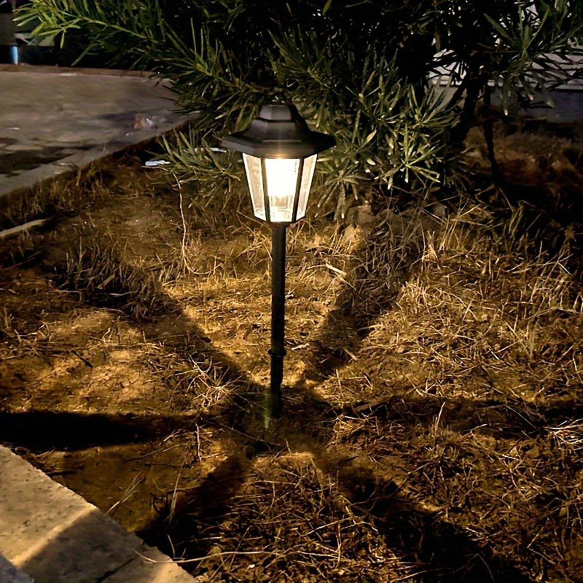 Lanterne solaire hexagonale installée sur un piquet dans un jardin