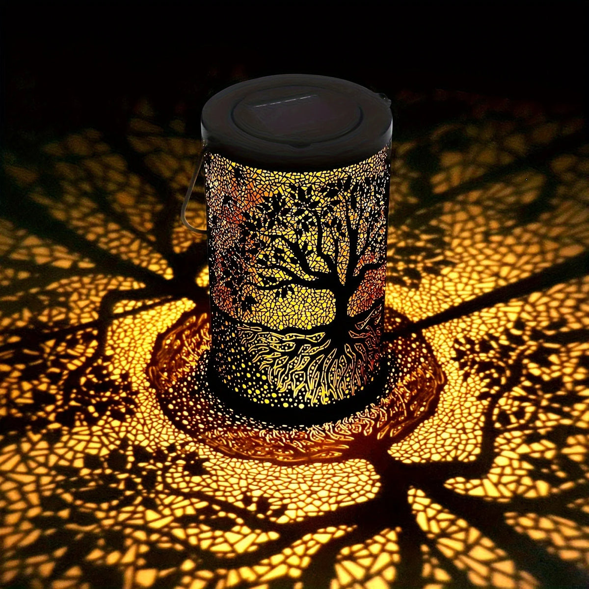 Lanterne solaire en métal ajouré à motif arbre projetant une lumière décorative au sol